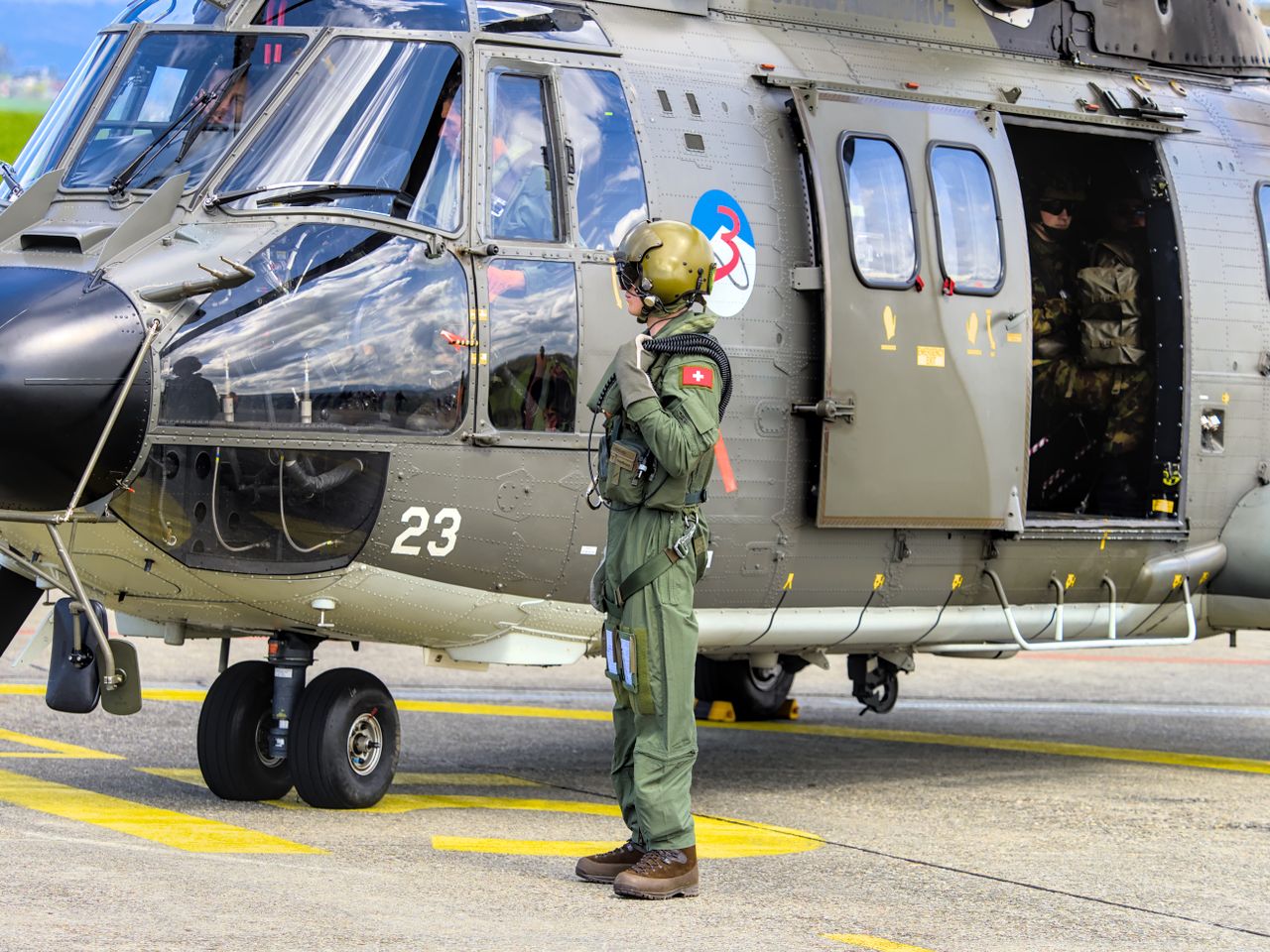about-02 Swiss soldier stands next to military helicopter at Payerne airfield. Aviation and defense theme.