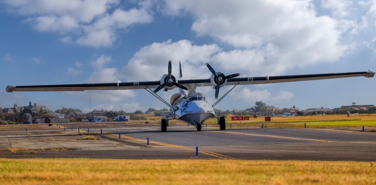 A vintage seaplane with dual propellers on a runway under a clear blue sky.