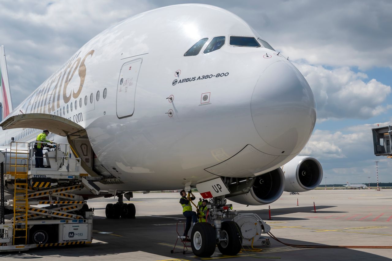 our-value An Airbus A380-800 aircraft being serviced on airport tarmac under a bright sky.